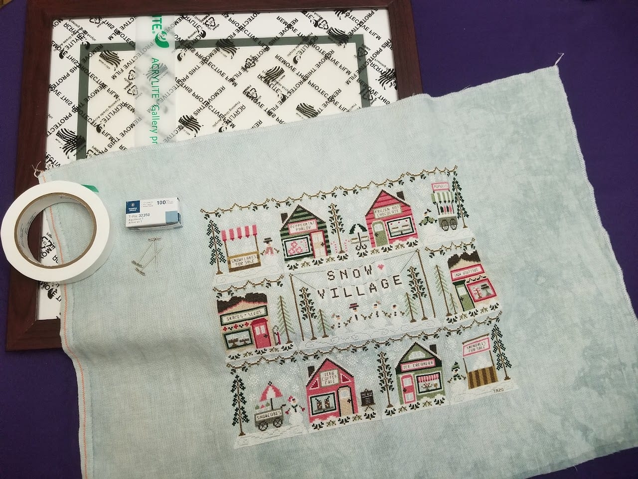 Flat lay of framing materials: foam core, framing tape, pins, and a frame