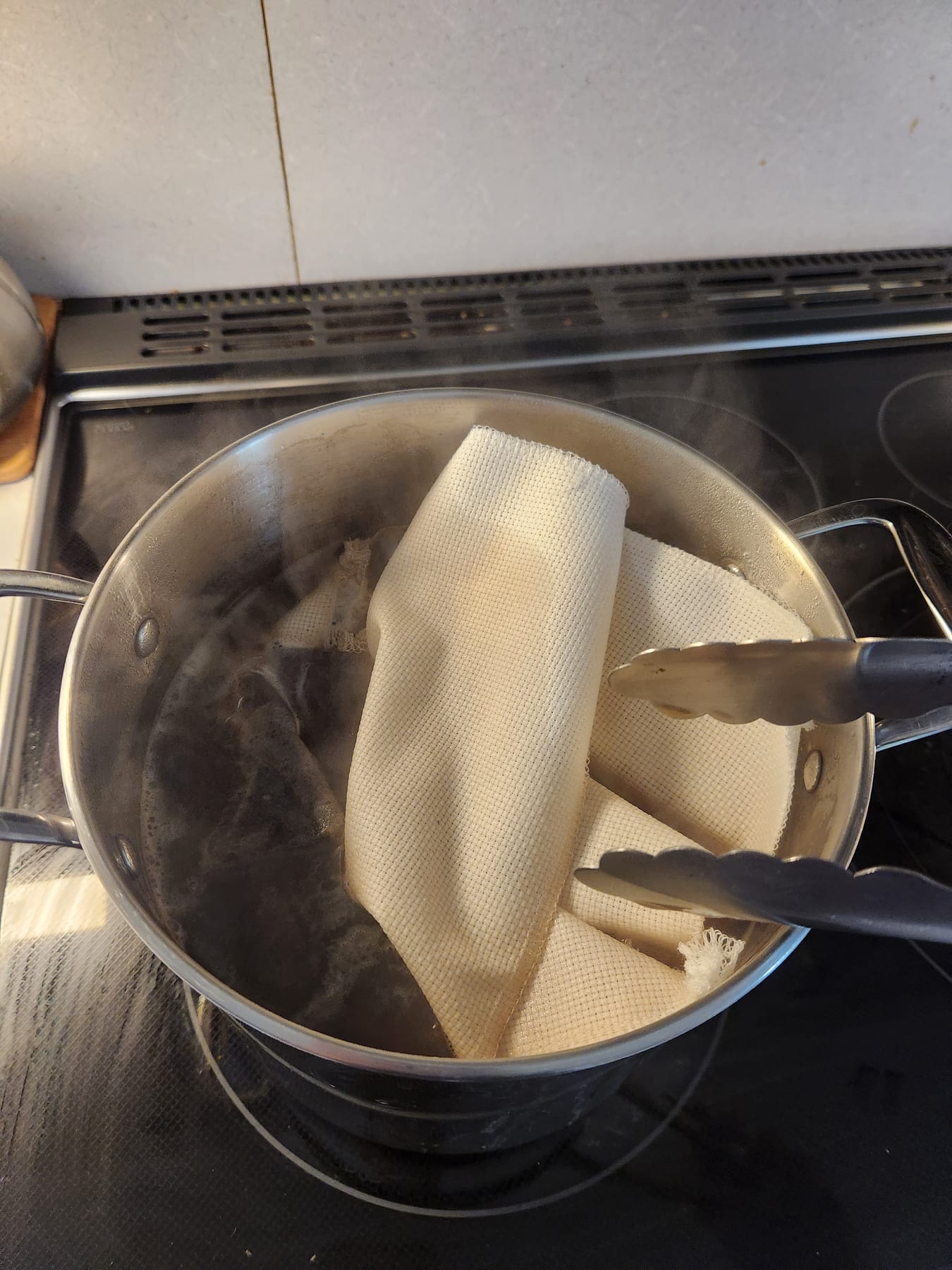 Fabric just placed into the pot of tea with tongs