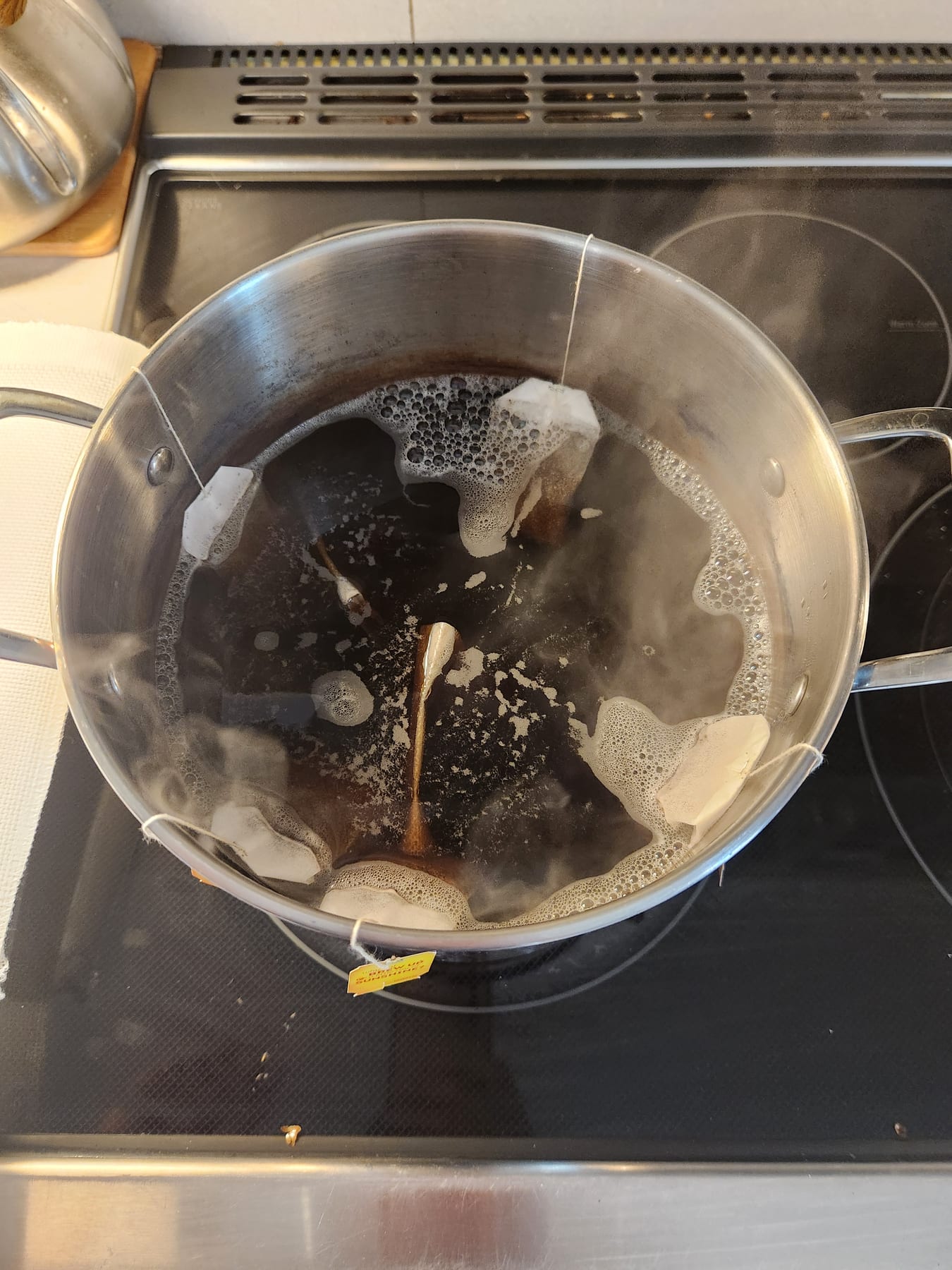 Tea bags and coffee steeping in a simmering pot of water