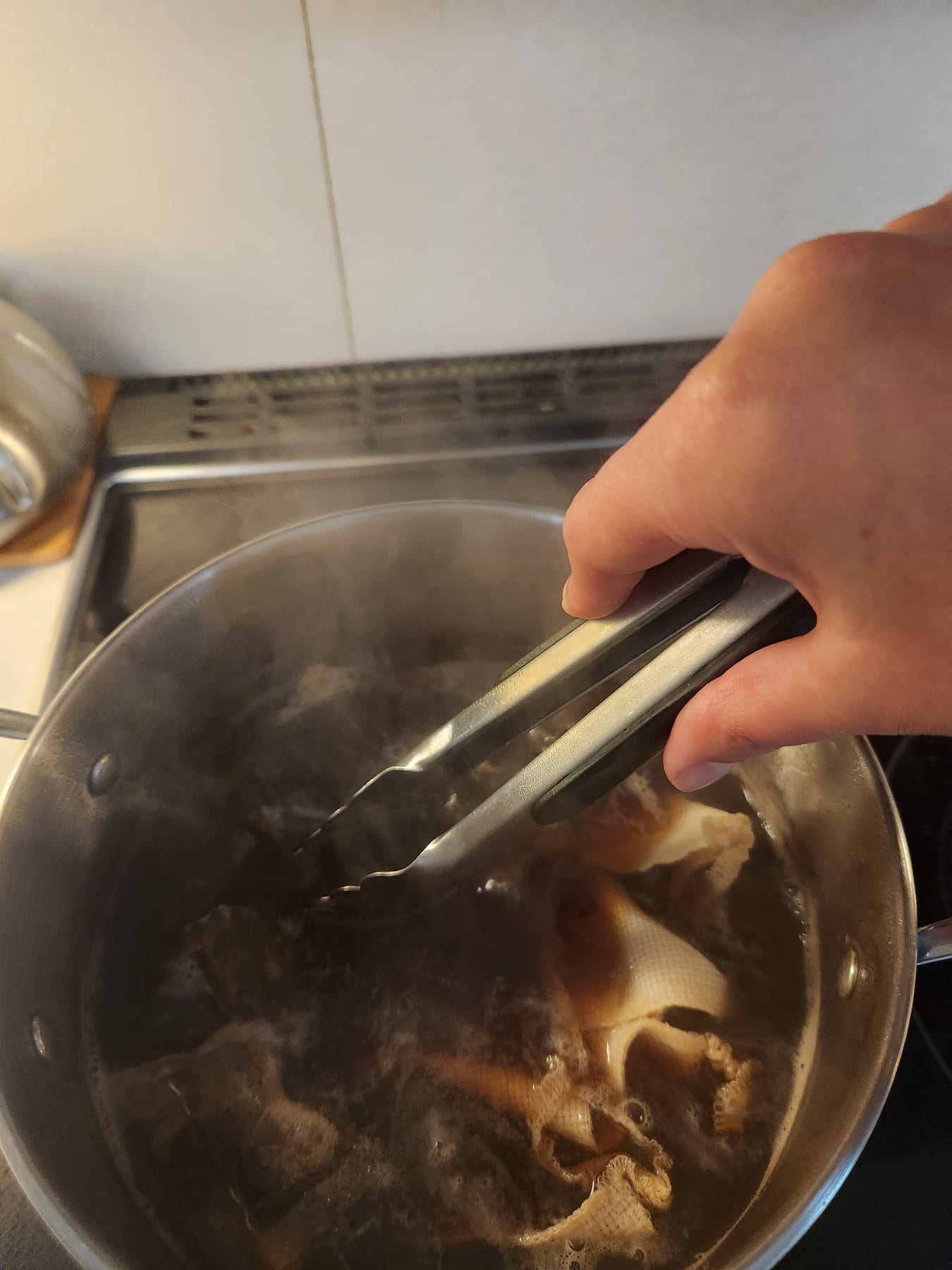 Pushing the fabric down into the dye bath with tongs