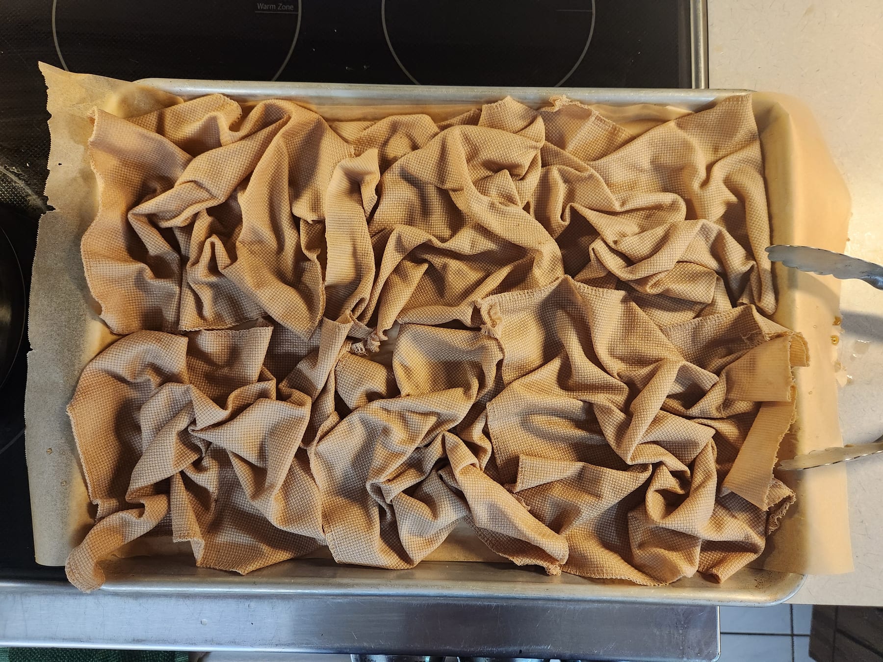 Wet dyed fabric scrunched into peaks and folds on the parchment-lined baking sheet
