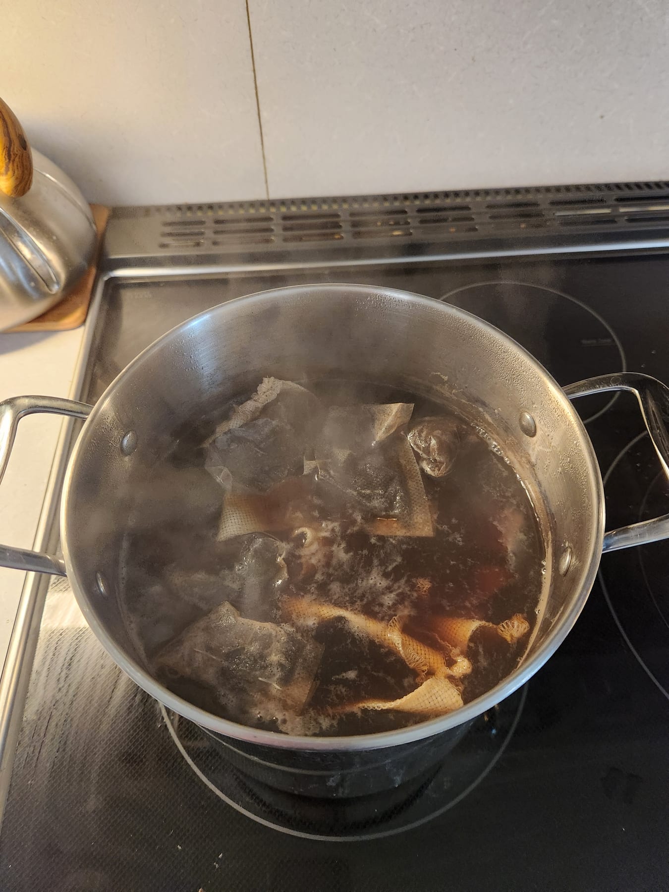 Fabric fully submerged in the dye bath with tea bags floating around it